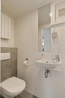 a white bathroom with a toilet and a sink at Have e nice stay! - Juul 18, free parking in Noordwijk