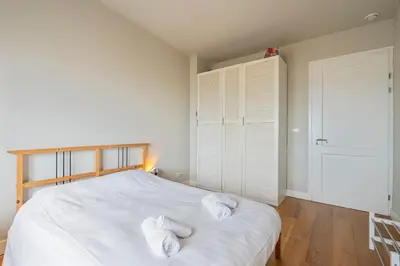 a bedroom with a white bed with towels on it at Sandhues Beachfront Apartment in Zandvoort