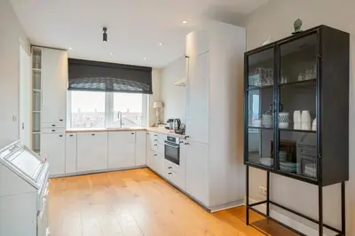 a kitchen with white cabinets and a large window at Sandhues Beachfront Apartment in Zandvoort