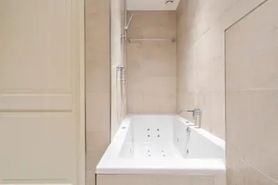 a white bath tub in a bathroom with a shower at Sandhues Beachfront Apartment in Zandvoort