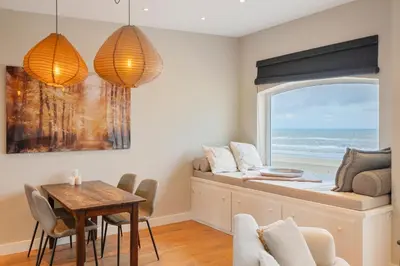 a dining room with a window and a table at Sandhues Beachfront Apartment in Zandvoort