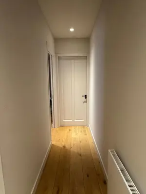 an empty hallway with a white door and wooden floors at The Park Loft in Amsterdam