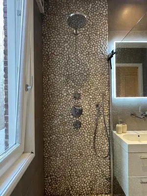 a bathroom with a shower with a stone wall at The Park Loft in Amsterdam