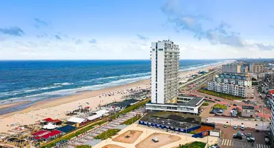 an aerial view of a beach and a tall building at Palm Beach apartments in Zandvoort