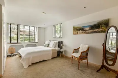a bedroom with a bed and a mirror and a chair at Palm Beach apartments in Zandvoort