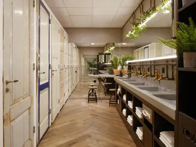a row of sinks in a public restroom with plants at CityHub Amsterdam in Amsterdam