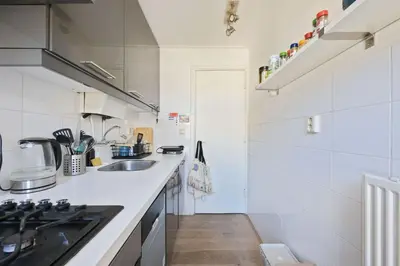 a white kitchen with a sink and a stove at Cozy place many rooms in Amsterdam