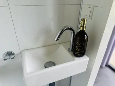 a bottle of wine is sitting on a bathroom sink at Stylish chalet in nature near Amsterdam in Halfweg
