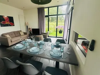 a dining table and chairs in a living room at Stylish chalet in nature near Amsterdam in Halfweg