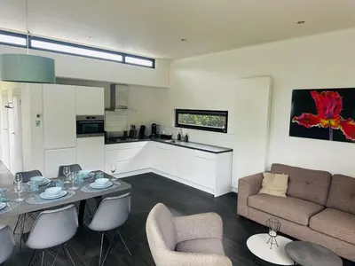 a living room with a couch and a table and chairs at Stylish chalet in nature near Amsterdam in Halfweg