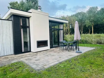 a patio with a table and chairs and a umbrella at Stylish chalet in nature near Amsterdam in Halfweg