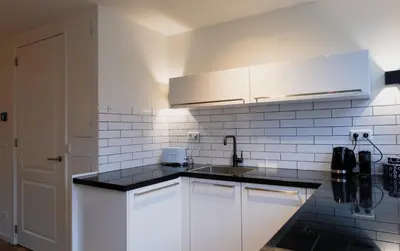 a kitchen with white cabinets and black counter tops at Klein Witje in Haarlem