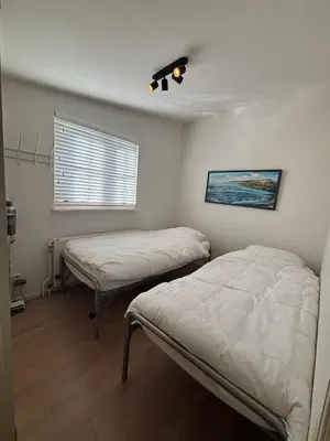 a bedroom with two beds and a window with a light at Vissershuisje Achterom 4 in Zandvoort
