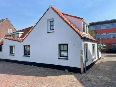a white house with a red roof on a street at Vissershuisje Achterom 4 in Zandvoort
