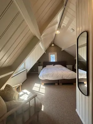 a attic bedroom with two beds and a mirror at Vissershuisje Achterom 4 in Zandvoort