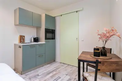 a kitchen with blue cabinets and a table with a vase at Studio Elysium in Zandvoort