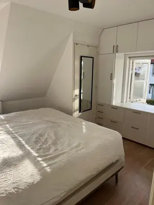 a white bedroom with a bed and a window at Luxurious sunny beach villa in Noordwijk