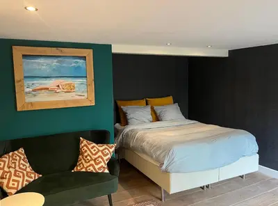 a bedroom with a bed and a chair and a painting at Luxurious sunny beach villa in Noordwijk