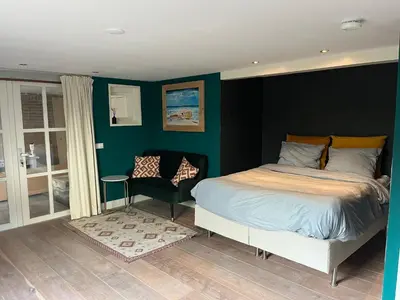 a bedroom with a bed and a chair at Luxurious sunny beach villa in Noordwijk