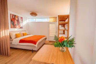 a bedroom with a bed and a vase of flowers on a table at De Strandgaper Egmond in Egmond aan den Hoef