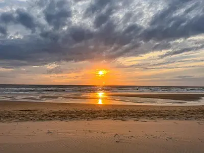 a sunset on a beach with the ocean at De Strandgaper Egmond in Egmond aan den Hoef