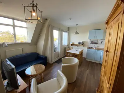 a living room with a blue couch and a kitchen at Stay in Bergen aan Zee in Bergen aan Zee