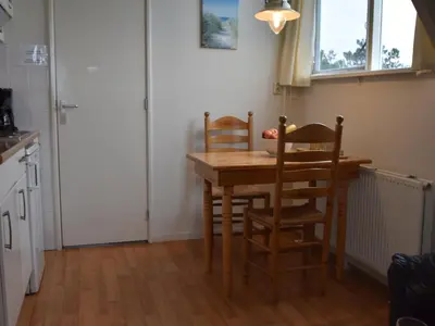 a kitchen with a wooden table and chairs at Apartment in Bergen aan Zee near Beach in Bergen aan Zee