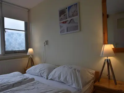 a bedroom with a bed with two lamps and a window at Apartment in Bergen aan Zee near Beach in Bergen aan Zee
