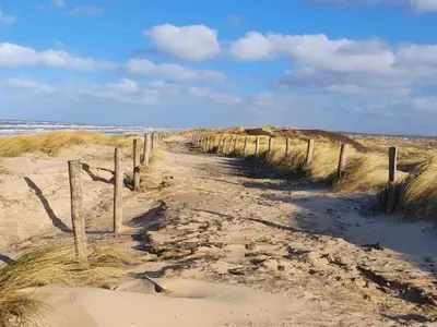 a dirt path through the sand on a beach at Dune Top Family Retreat in Bergen aan Zee
