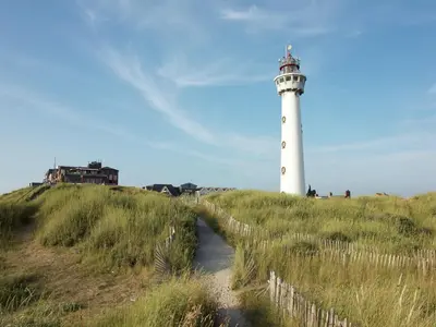 a lighthouse on a grassy hill with a path leading to it at Apartment in Bergen near the Beach in Bergen aan Zee
