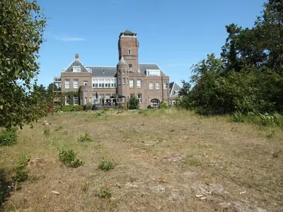 an old house on top of a grassy hill at Apartment in Bergen near the Beach in Bergen aan Zee