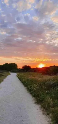 a dirt road with the sunset in the background at Beautiful loft in Katwijk aan Zee in Katwijk aan Zee
