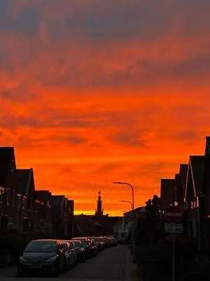 a sunset over a street with cars parked on the street at Beautiful loft in Katwijk aan Zee in Katwijk aan Zee