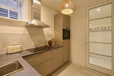 a kitchen with white cabinets and a sink and a window at Appartement B Rosita in Twisk