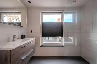 a bathroom with a sink and a window with a blind at Haarlem Hart in Haarlem