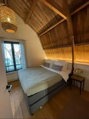 a bedroom with a large bed with a wooden ceiling at Het Binnenhuys, Luxe B&B in Noordwijk met tuin, vlakbij het strand in Noordwijk