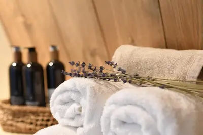a bunch of towels and a vase with lavender at Het Binnenhuys, Luxe B&B in Noordwijk met tuin, vlakbij het strand in Noordwijk