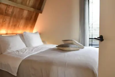 a bedroom with a white bed with a window at Het Binnenhuys, Luxe B&B in Noordwijk met tuin, vlakbij het strand in Noordwijk
