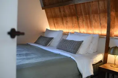 a bed with a wooden headboard and pillows on it at Het Binnenhuys, Luxe B&B in Noordwijk met tuin, vlakbij het strand in Noordwijk
