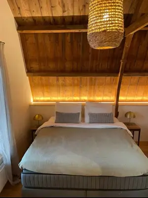a bedroom with a large bed with a wooden ceiling at Het Binnenhuys, Luxe B&B in Noordwijk met tuin, vlakbij het strand in Noordwijk