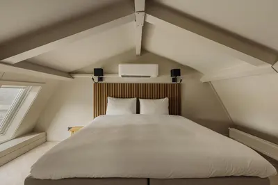 a bedroom with a large white bed in a attic at De Ooievaar in Naarden