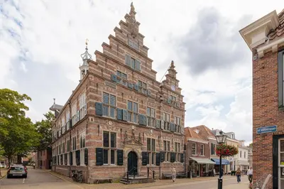 an old brick building with a clock tower on a street at De Ooievaar in Naarden