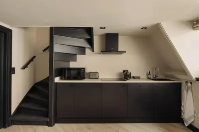 a kitchen with black cabinets and a sink and microwave at De Ooievaar in Naarden
