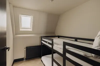 two bunk beds in a small room with a window at De Ooievaar in Naarden
