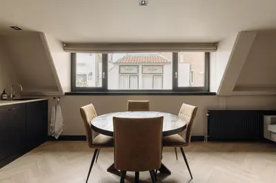 a dining room with a table and chairs and a window at De Ooievaar in Naarden