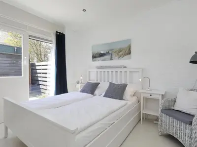 a white bedroom with a large bed and a window at Holiday Home Zonneschijn by Interhome in Noordwijkerhout