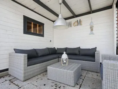 a patio with a couch and two wicker chairs at Holiday Home Zonneschijn by Interhome in Noordwijkerhout