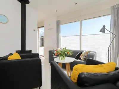 a living room with two black couches and a fireplace at Holiday Home Zonneschijn by Interhome in Noordwijkerhout