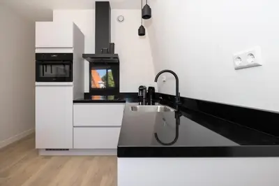 a kitchen with white counters and a sink at Hoorn Center - Dashing Hoorn in Hoorn