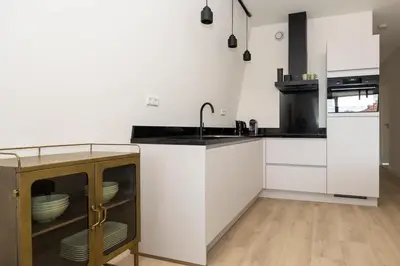 a kitchen with white cabinets and a sink at Hoorn Centre - Catching Hoorn in Hoorn